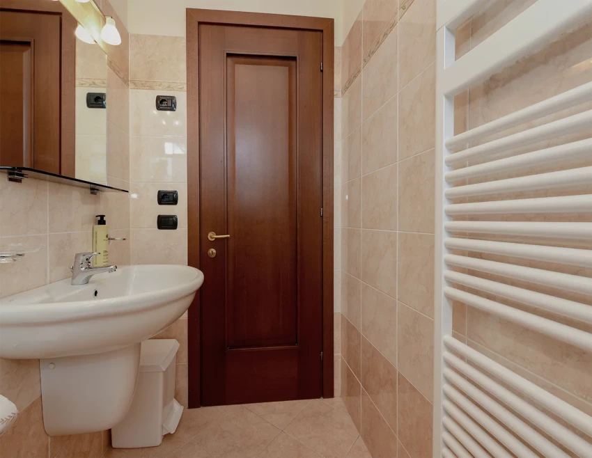 Bagno con lavabo, piastrelle beige e scaldasalviette vicino al Lago di Garda