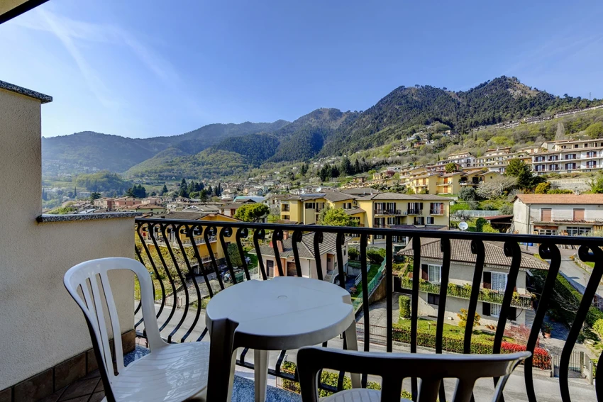 Balcone con tavolo e sedie, vista sul borgo e sulle montagne del Lago di Garda