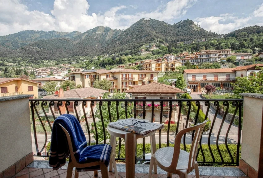Balcony with two chairs and table overlooking hillside village and mountains by Lake Garda