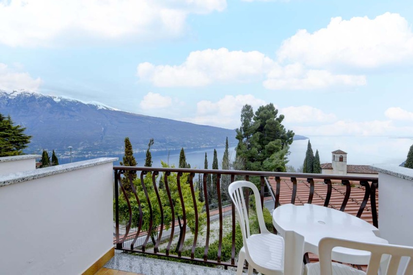 Balkon mit Tisch und Stühlen, Blick auf den Lago di Garda, Berge und Zypressen