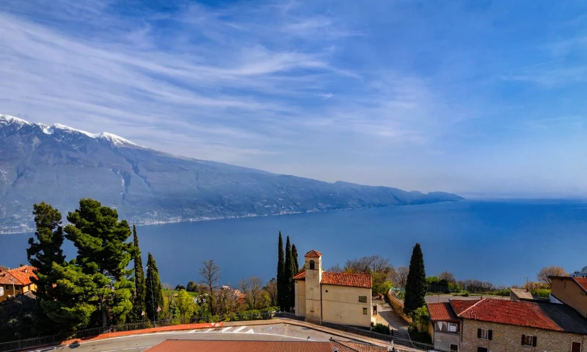 Panorama sul lago di garda con borgo, chiesa e montagne sullo sfondo