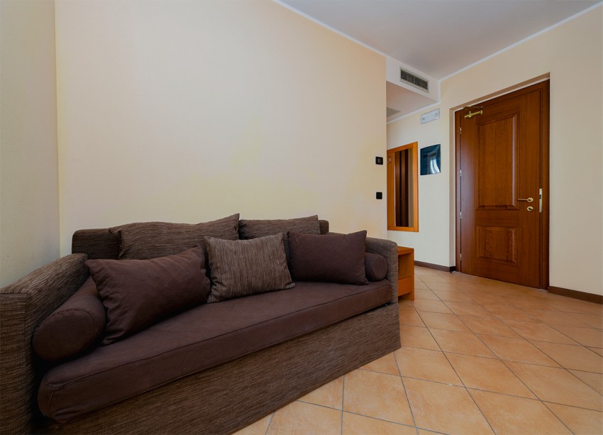 Cozy living area with brown sofa, cushions and wooden door, near Lago di Garda.