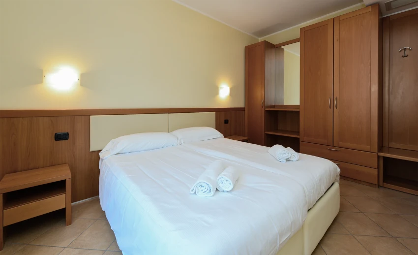 Camera d'hotel con letto matrimoniale e armadi in legno al Lago di Garda