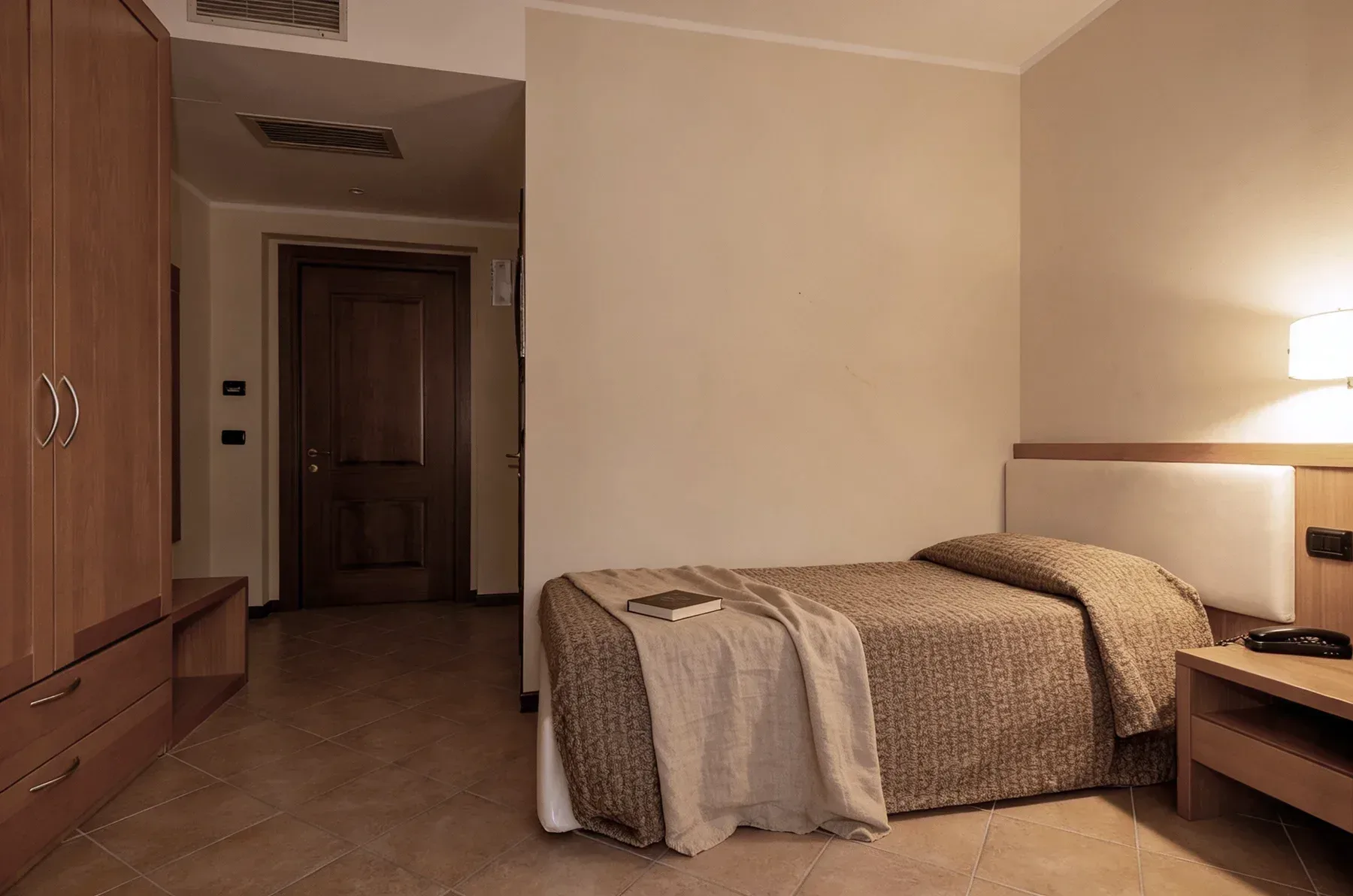 Camera singola accogliente con letto e comodino, vicino al Lago di Garda