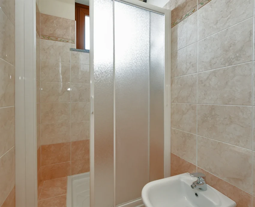 Tiled bathroom with frosted glass shower and small sink near Lago di Garda