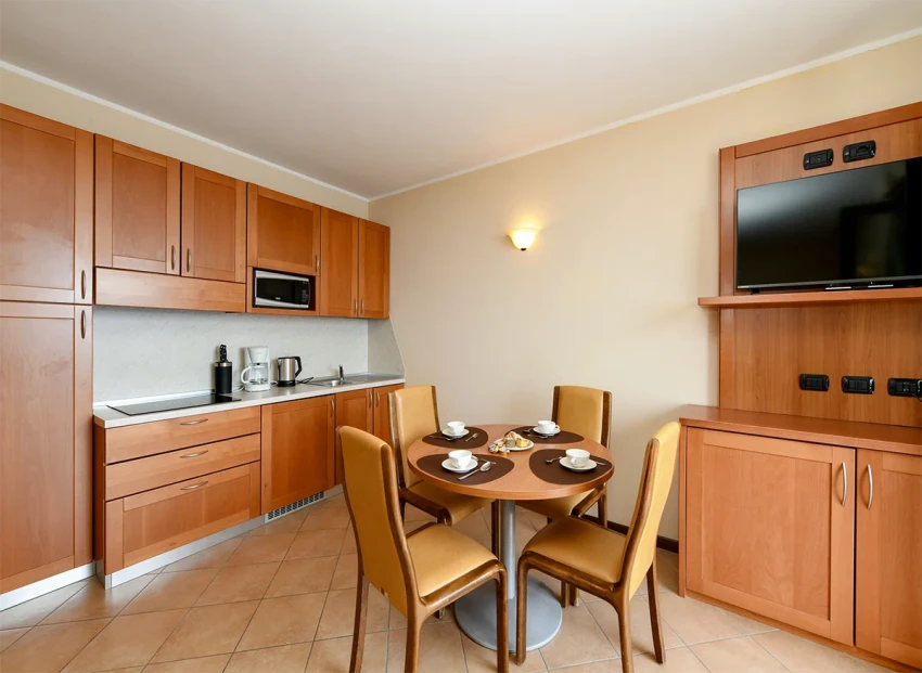 Kitchenette with round dining table and TV in apartment by Lake Garda