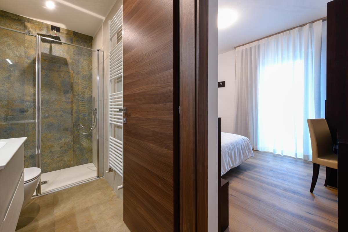 Modern bathroom with glass shower and bedroom view, Lago di Garda