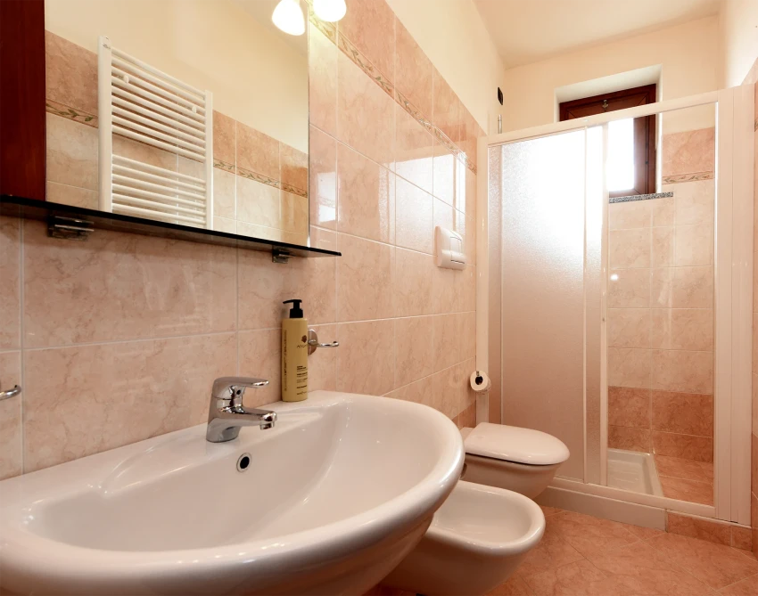 Bright tiled bathroom with sink, bidet, toilet and shower, Lago di Garda