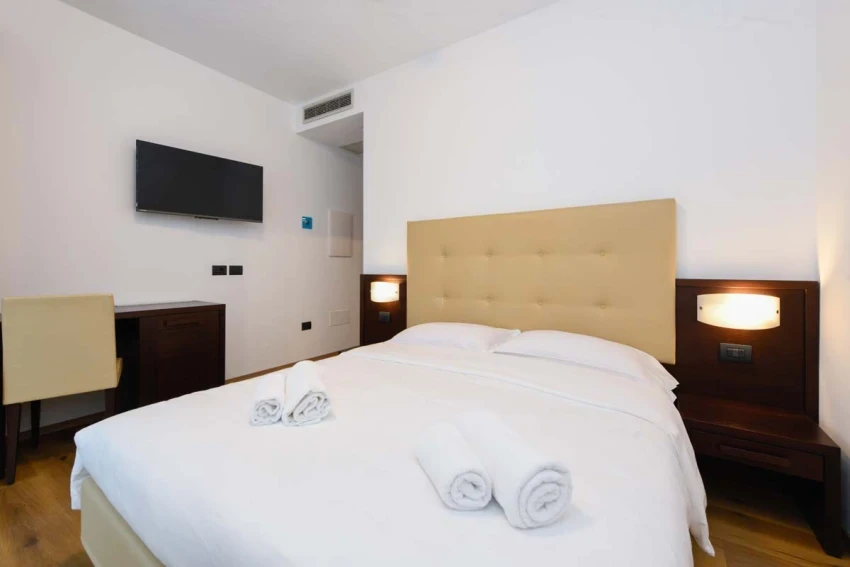 Modern hotel room with double bed, TV and towels near Lago di Garda.