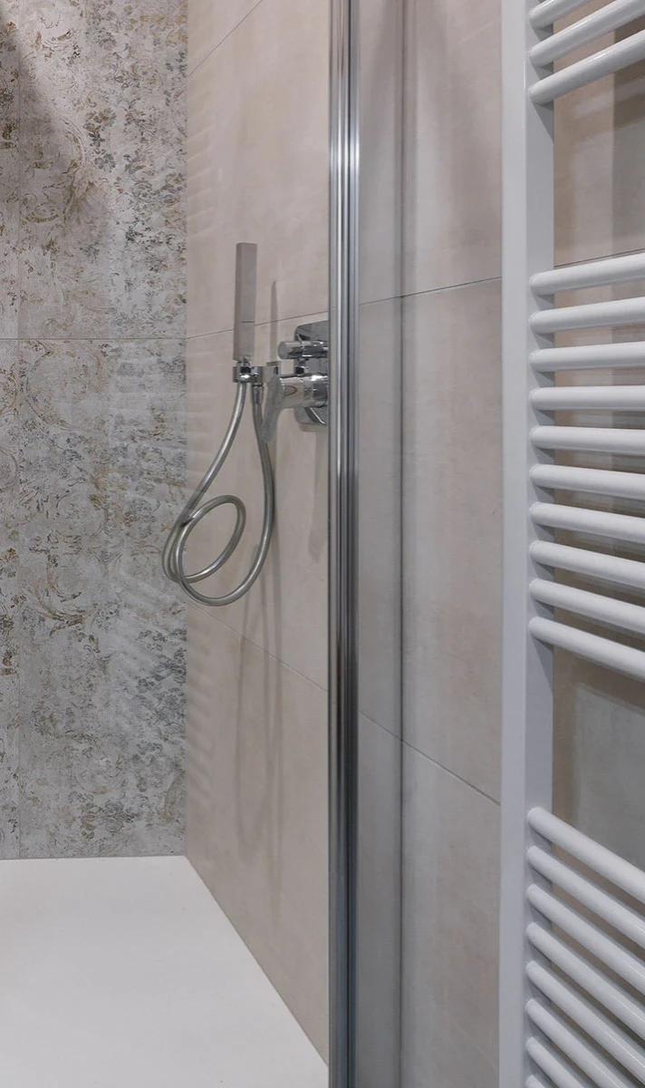 Moderne Dusche mit verchromter Handbrause und Fliesenwand am Gardasee