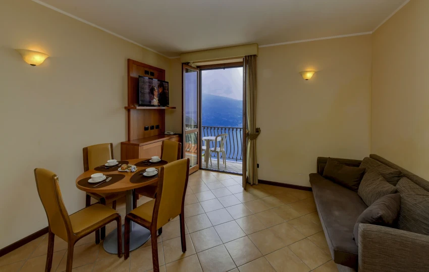 Soggiorno con tavolo e divano, balcone vista lago di Garda