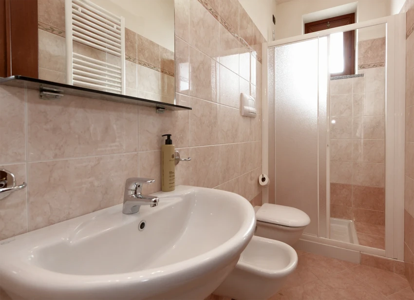 Bright tiled bathroom with sink, bidet, toilet and shower near Lake Garda